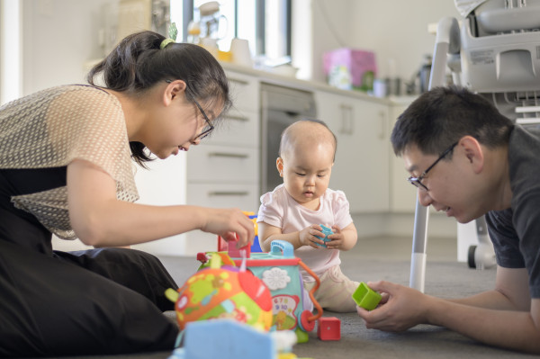 Parents playing on the floor with their child.