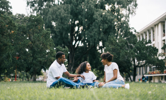 family sitting on grass near building 1128316