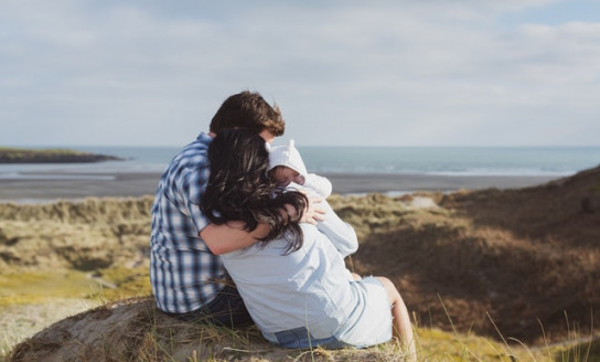 man and woman sitting on stone carrying baby 2120220